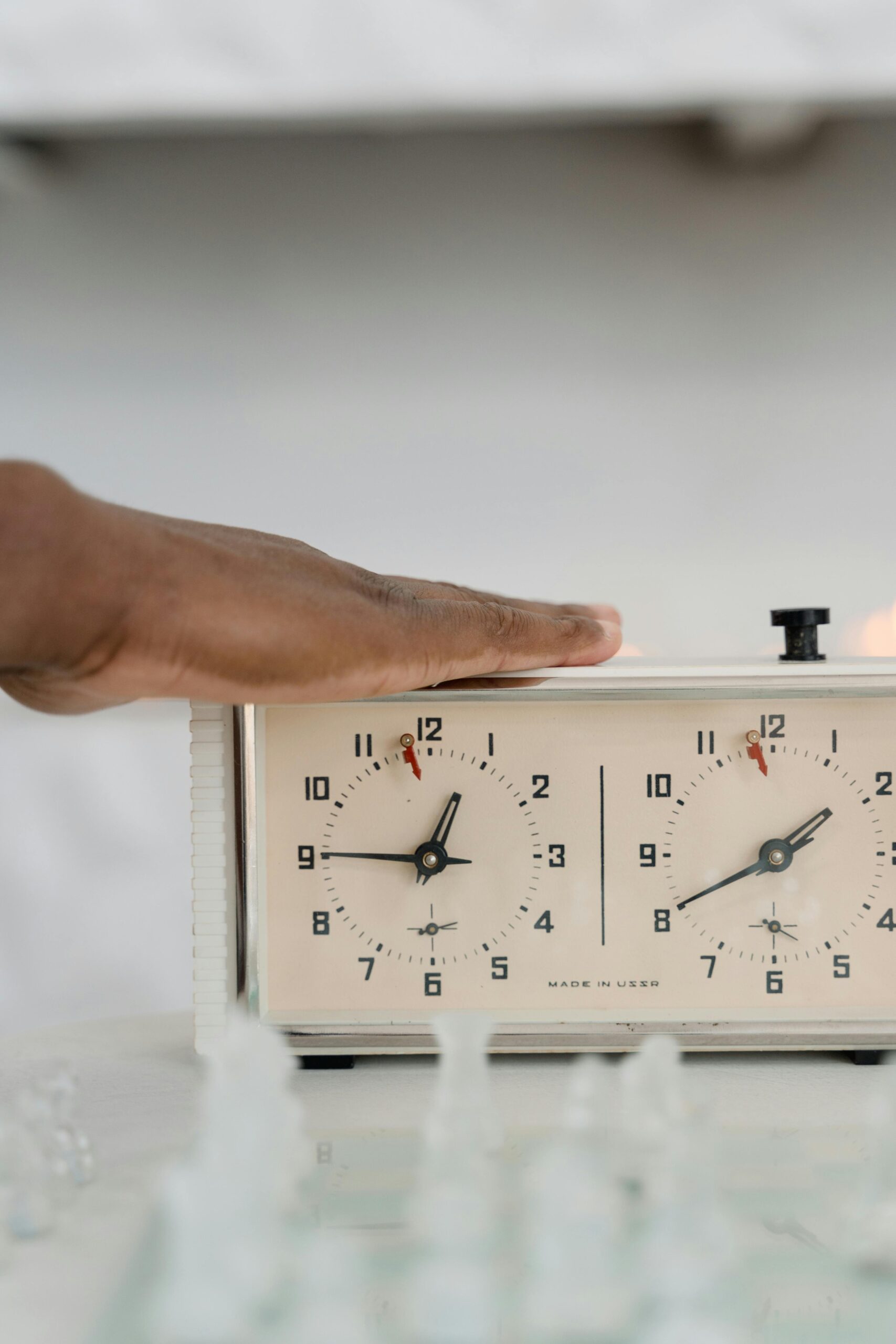 A chess player's hand operating a classic analog chess clock during a game.